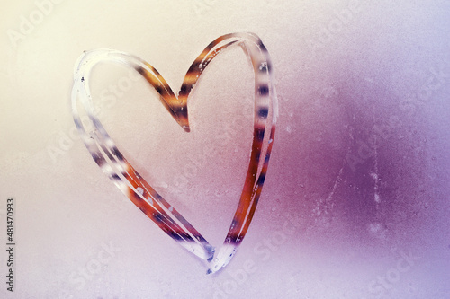 Hand-drawn heart on frost on a frozen window glass on a sunny day. Romantic background for Valentine's day photo