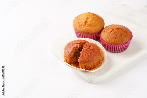 Several homemade white and pink muffins on marble board on white surface