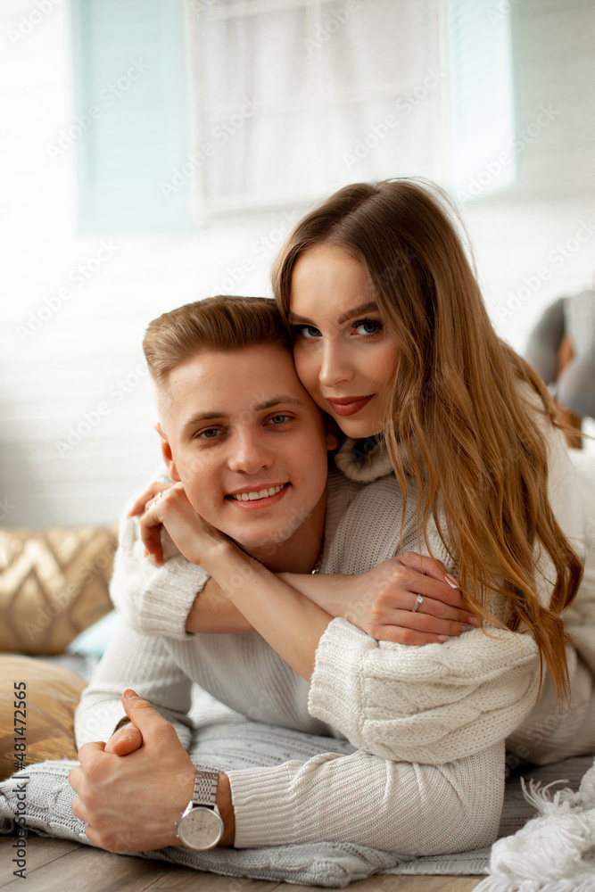 Smiling young man and woman lying on the floor and hugging while celebrating some holiday, possibly st valentines day Smiling young man and woman lying on the floor and hugging while celebrating some holiday, possibly st valentines day
