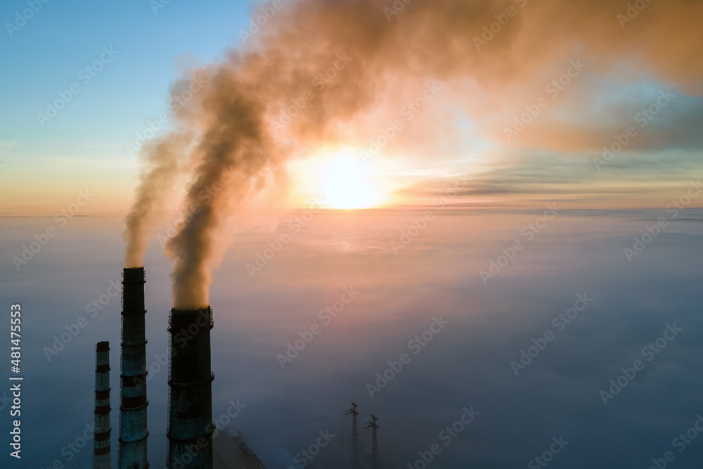 Obraz premium Aerial view of coal power plant high pipes with black smoke moving up polluting atmosphere at sunset
