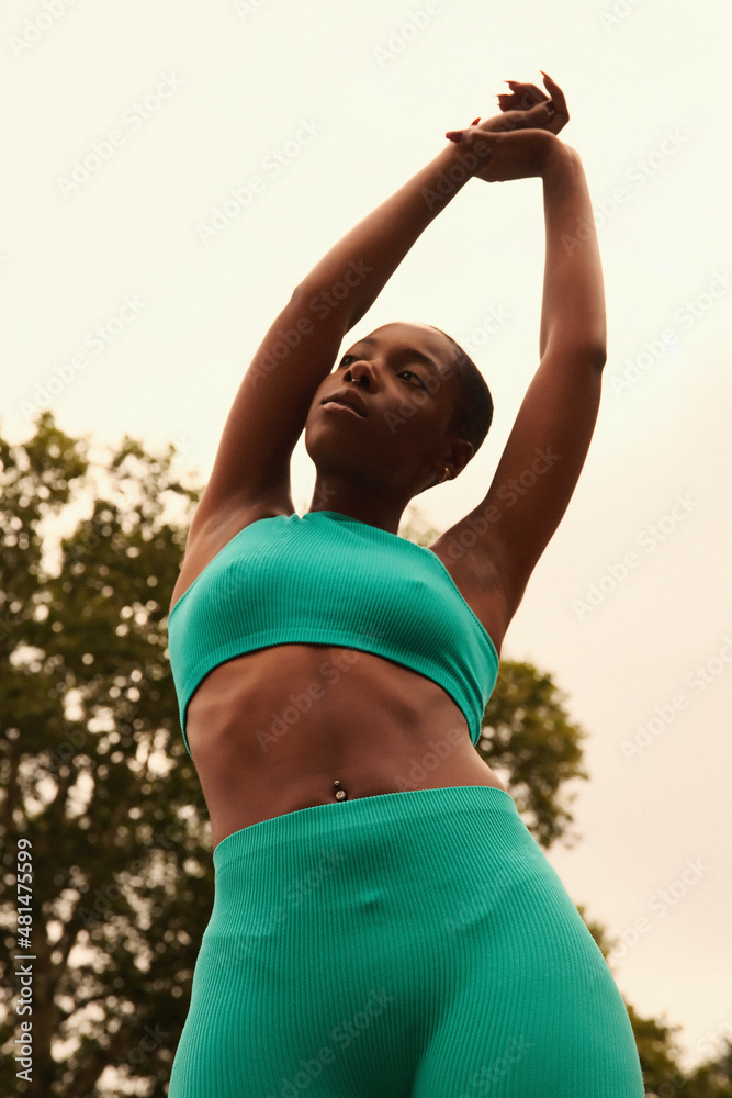Low angle view of woman in sports clothing stretching in park Low angle view of woman in sports clothing stretching in park