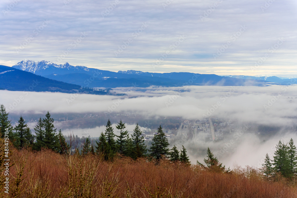 Fraser Valley winter cloud inversion over Port Moody, BC, at Burrard Inlet with alpine mountain backdrop.