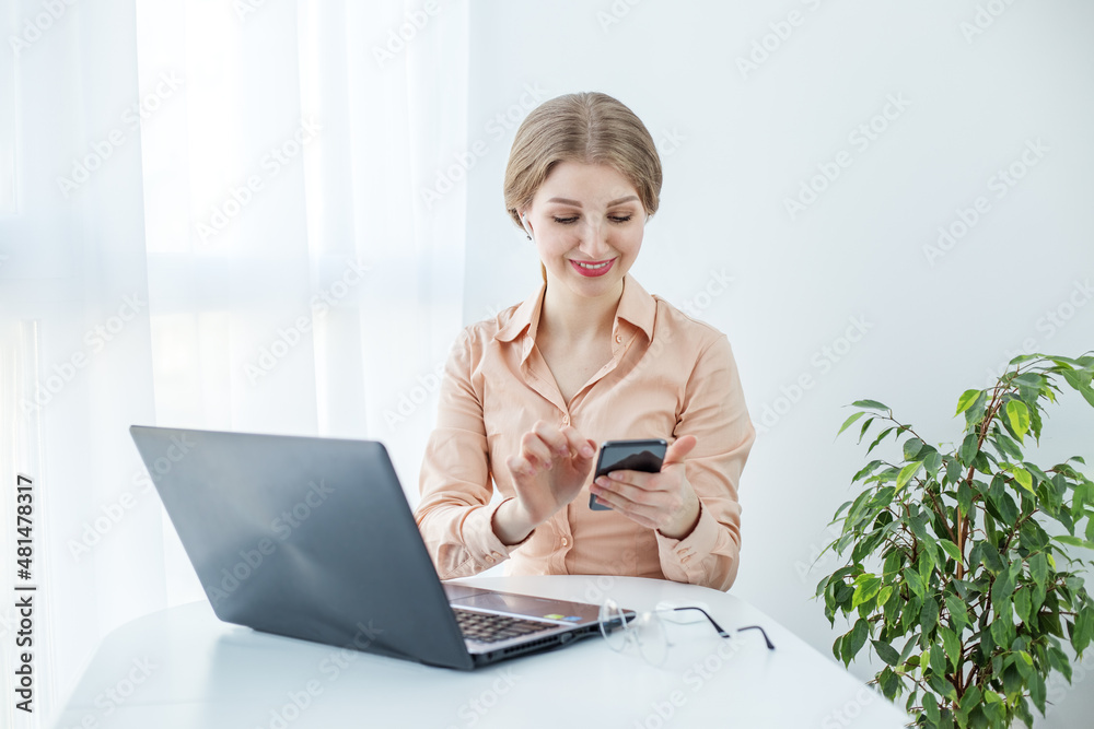 Smiling business woman working with laptop and smartphone. Modern bright office. Smiling business woman working with laptop and smartphone. Modern bright office.