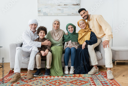 happy multiethnic muslim family looking at camera on sofa at home.