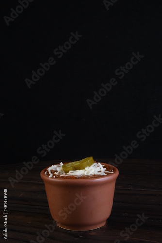 mexican chili, beans with ground beef pepper in porcelain bowl isolated on black background