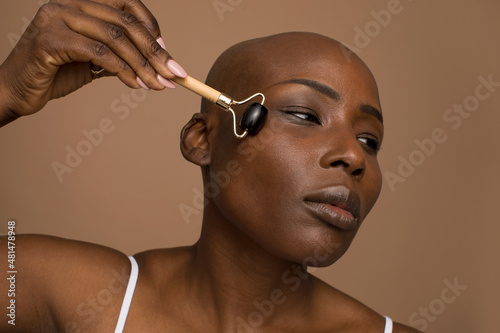 Studio portrait of woman massaging face with stone roller
