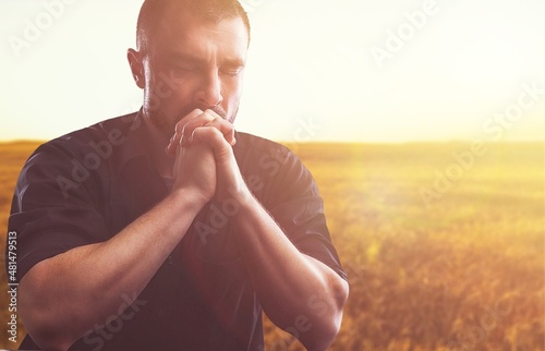 Human praying on the holy bible in a field during beautiful sunset Fototapeta
