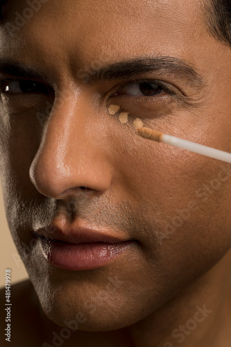 Close-up of man applying foundation under eye