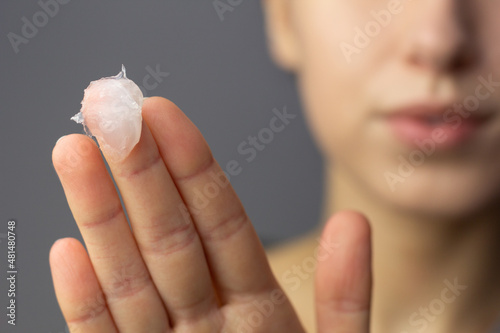 A young woman is applying petroleum jelly to her face. Concept of slugging. photo