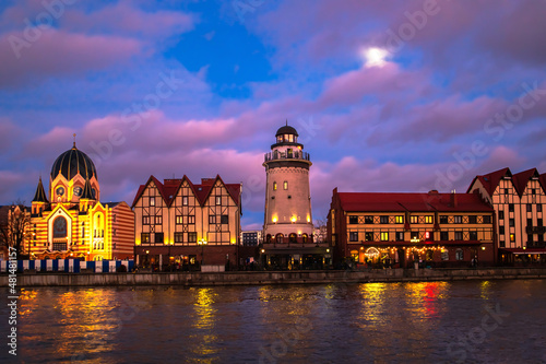 Fishing village in Kaliningrad at night. Stylization of ancient Europe, lighthouse, ancient houses. © lizavetta