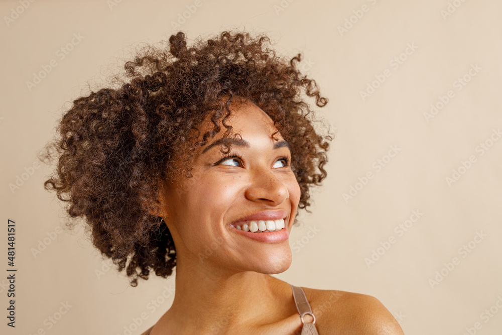Cheerful multiracial woman posing against beige wall Cheerful multiracial woman posing against beige wall