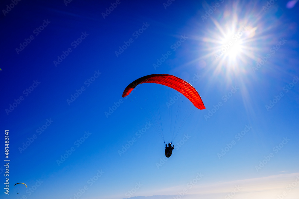 Paragliding above mountain peaks and white clouds during winter blue sunny day. Paragliding above mountain peaks and white clouds during winter blue sunny day.