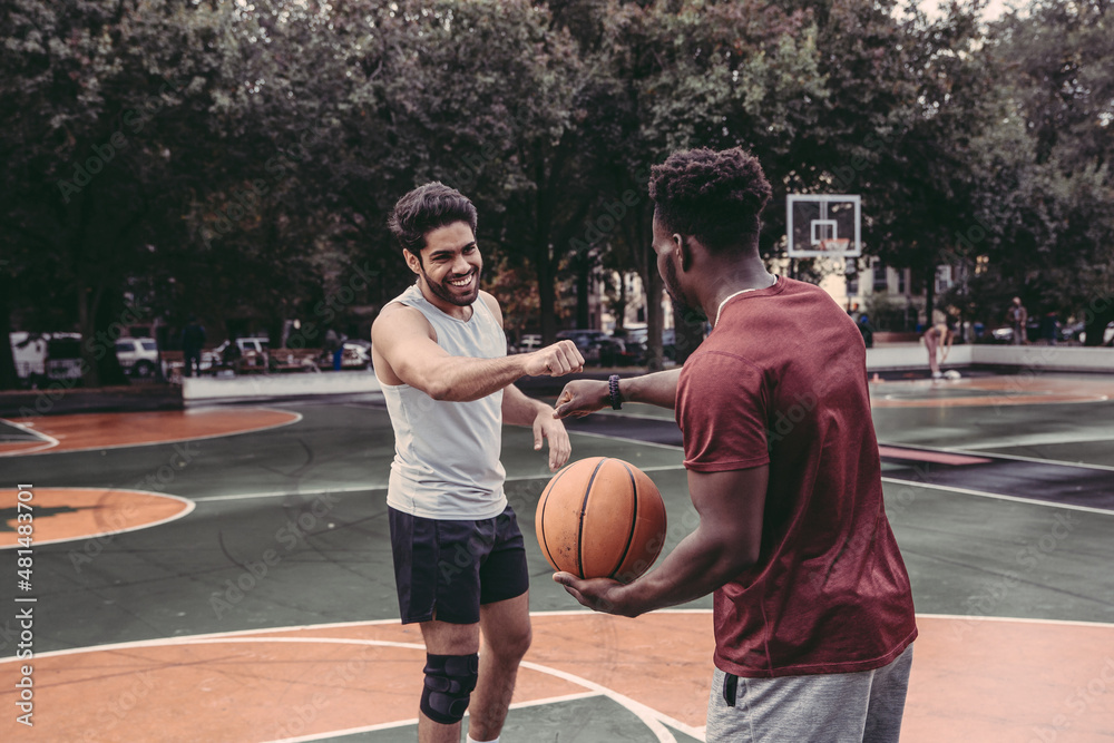 USA, Pennsylvania, Philadelphia, Men bumping fists at basketball court in park
