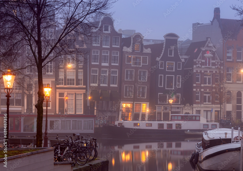 Beautiful old houses on the city embankment of Amsterdam in the fog.