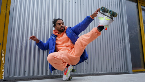 Young man wearing roller skates stretching by iron wall