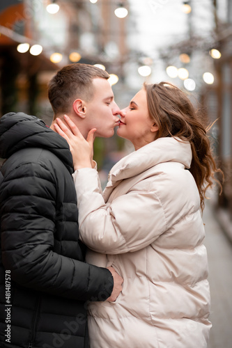 Happy man kissing his woman in the street. The guy in love takes care of the girl. Couple enjoying life outdoors. The concept of light valentine's day, gifts © Granmedia