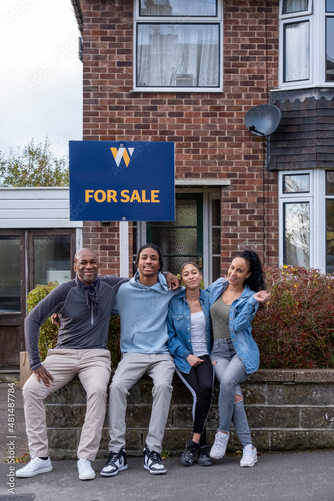 Fototapeta premium Portrait of family with teenage daughter and son in front of new house