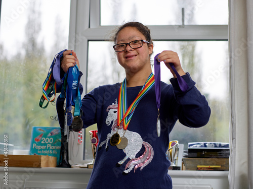 Foto Portrait of girl with Down syndrome showing medals