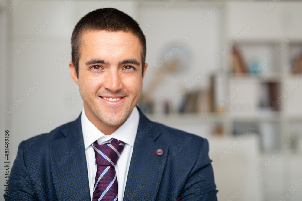Portrait of smiling businessman who is at his work place in office - obrazy, fototapety, plakaty 