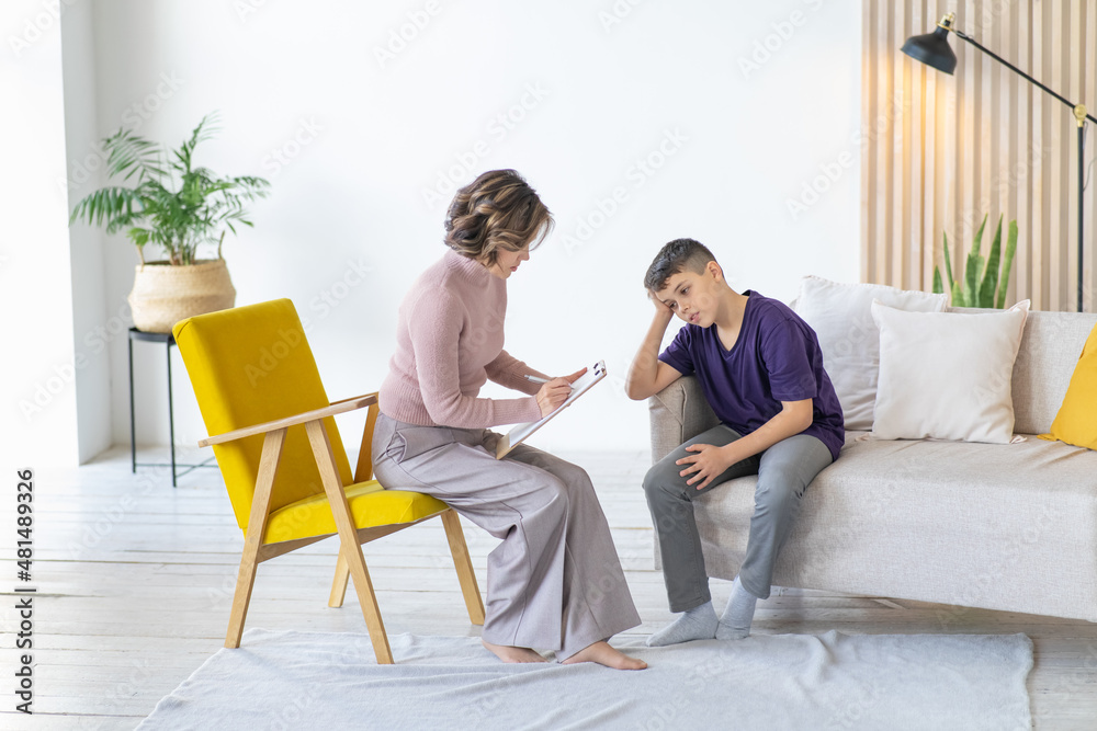 Teenager holds his head and worries. Woman psychologist. Appointment with teenage psychologist. Teenager holds his head and worries. Woman psychologist. Appointment with teenage psychologist.