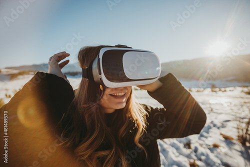 happy woman looking through vr glasses outdoors in snow