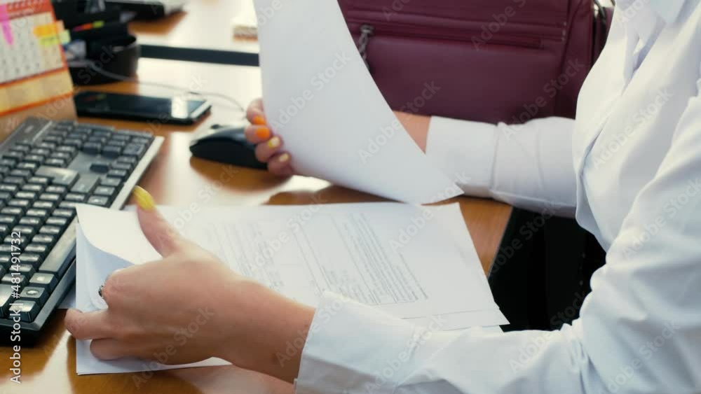 Office worker looks through documents. Preparing documents for the client. Documentation, reporting, bookkeeping Office worker looks through documents. Preparing documents for the client. Documentation, reporting, bookkeeping