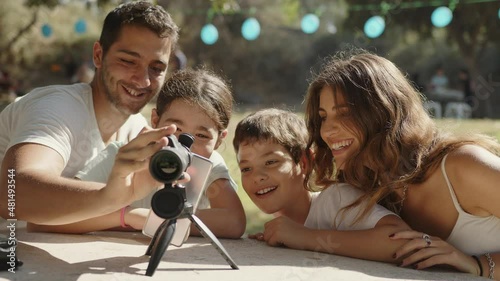 A happy family is excited at the park enjoying their monocular telescope. Medium shot