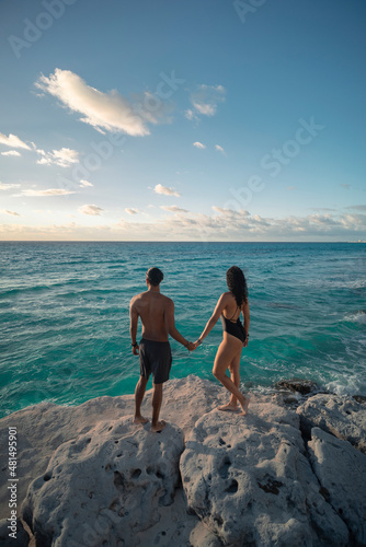 Obraz na płótnie Pareja de jóvenes latinos enamorados tomados de las manos en la playa, sobre las