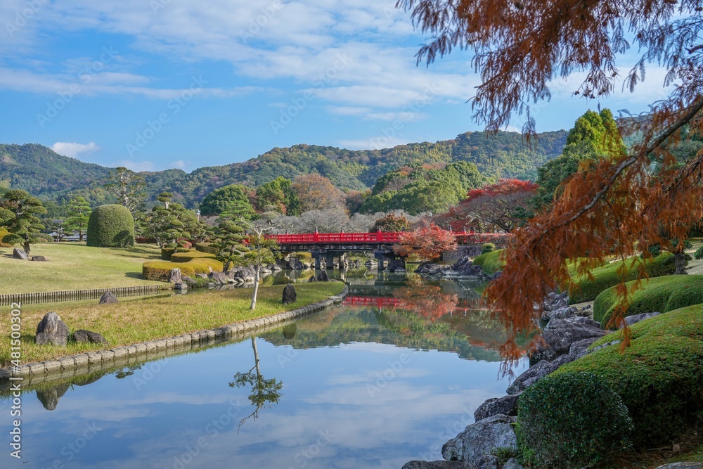 鮮やかな朱色の橋がある日本庭園の秋の情景＠愛媛