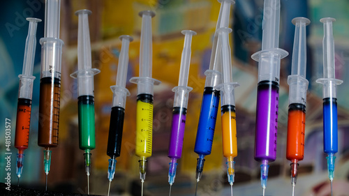 Multicolored vaccines in disposable syringes on the background of a bright picture. Modern means of health protection.