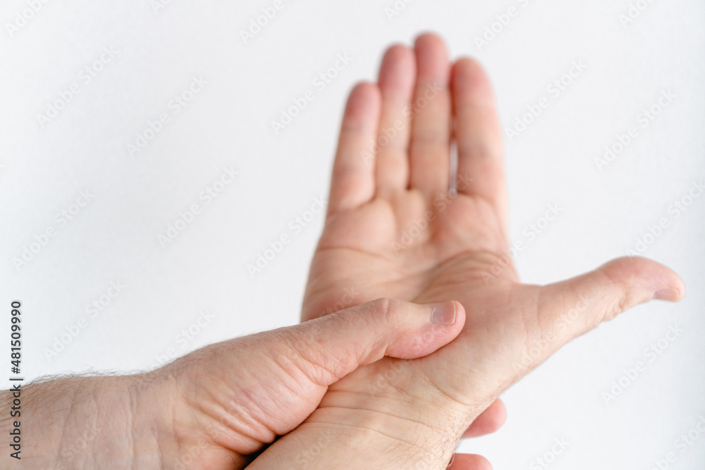 Hand of an elderly person with age spots doing thumb extension exercises while the other hand holds the wrist. Hand of an elderly person with age spots doing thumb extension exercises while the other hand holds the wrist.
