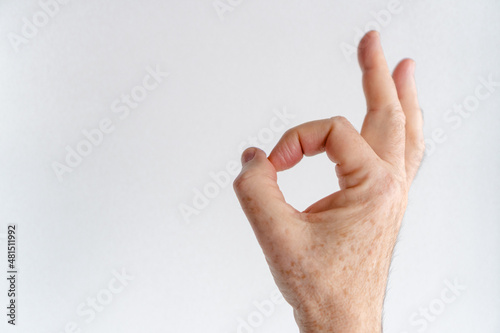 Hand of an elderly person with old age spots making the okay gesture. Copy space.