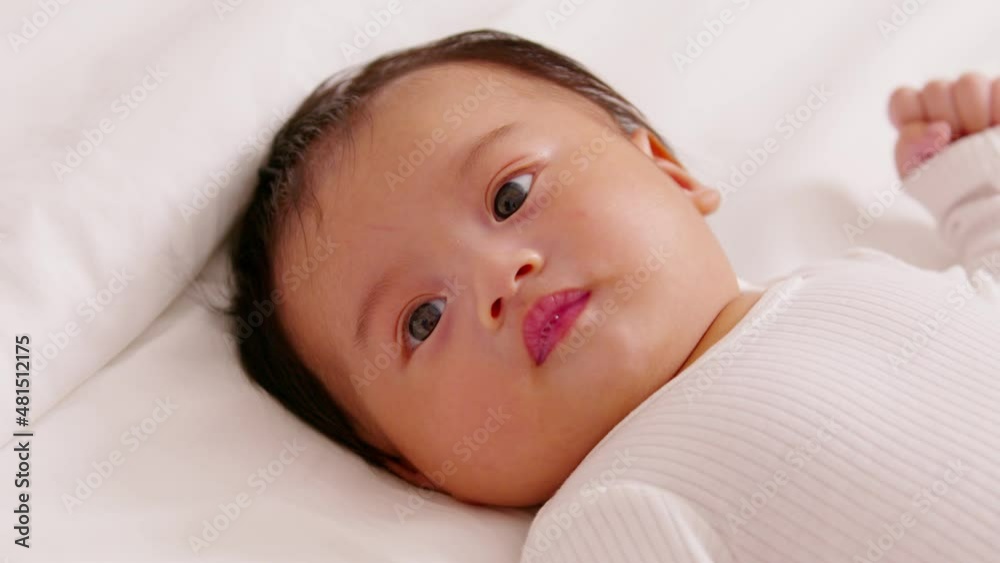 happy newborn baby lying on a white bed and blanket comfortable and safety.Cute Asian newborn looking around on bed.Newborn Baby Care concept