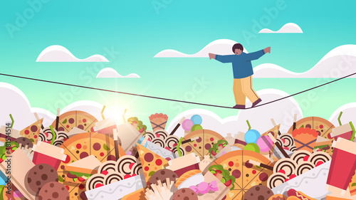 overweight boy balancing on rope above junk food assortment of fast food unhealthy nutrition junkfood addiction