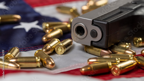 Detail of gun barrel with many bullets on American flag. Concept of gun control and carry of firearms in the USA. American guns and ammunition.