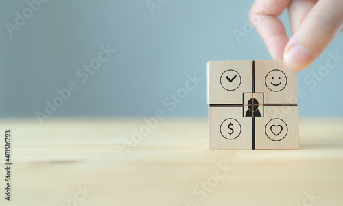 Work life balance concept. Comparison work, finance and happyness. Hand holds the wooden cubes with happiness icon standing with work, money, healthy icon on grey background and copy space. Banner.
