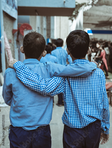 Two blind boys supporting each other as they walk cautiously on a busy street. Sightless children holding each other to protect from obstacles on their path.