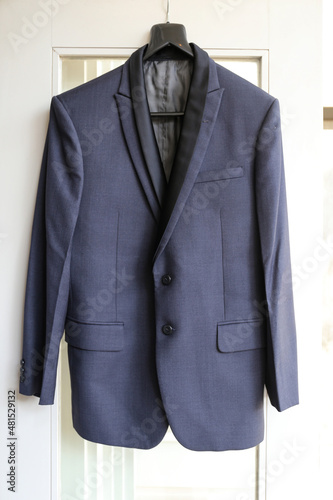 Stylish groom suit in dressing room indoors, hanging at the door.