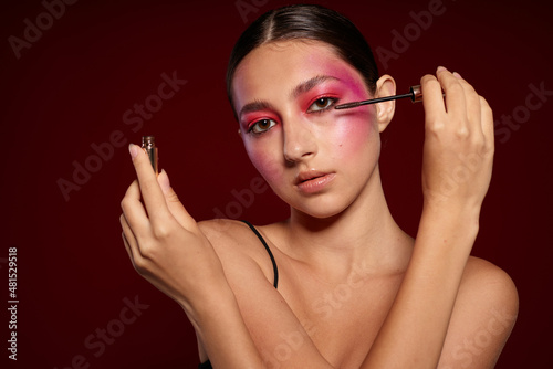 Portrait of beautiful young woman makeup emotions cosmetics hair care mascara pink background unaltered
