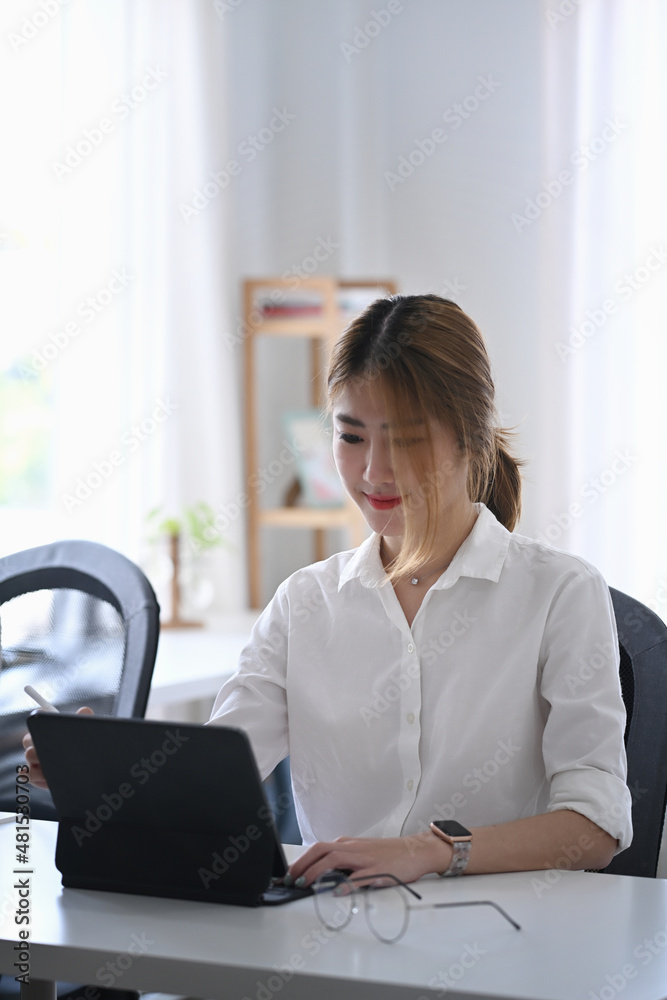 Asian woman working with computer tablet at modern office.
