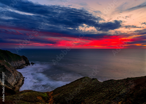 Coastal cliffs and silky ocean by Devil's Slide trail in California at sunset