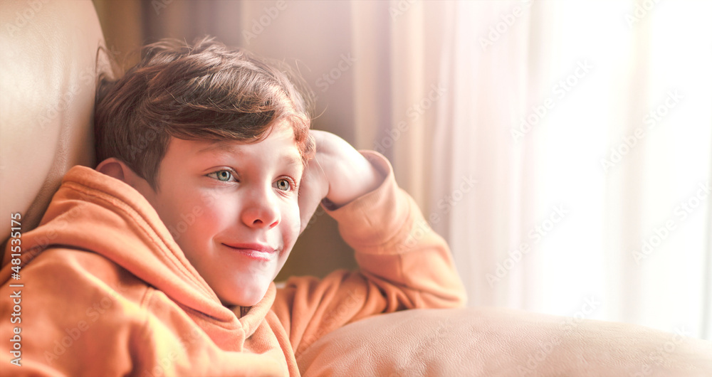 The boy is smiling dreamily sitting on the couch The boy is smiling dreamily sitting on the couch