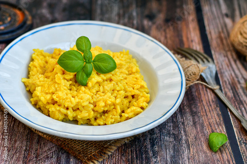  Italian  creamy risotto milanese  with parmesan cheese and fresh basil on rustic background