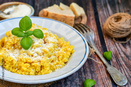 Photo Italian  creamy risotto milanese  with parmesan cheese and fresh basil on rusti