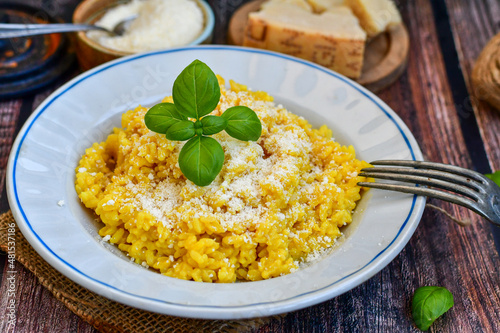  Italian creamy risotto milanese with parmesan cheese and fresh basil on rustic background