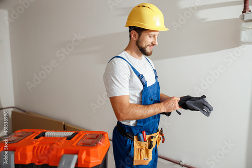 Bilde på lerret Professional electrician technician in uniform and hard hat putting on protectiv