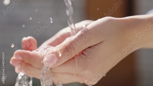 a stream of wet transparent clean water is poured onto the hands, observe the hygiene of clean human skin, moisturize and wash fingers, clean and wash after work, wash off the dirt, close-up