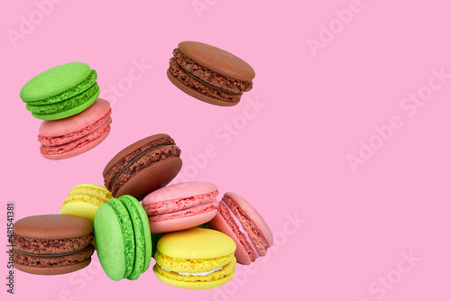 French macaroons flying in the air isolated on a pink background.