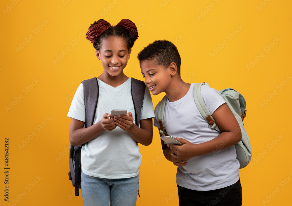 Afro-american boy and girl schoolers using smartphones