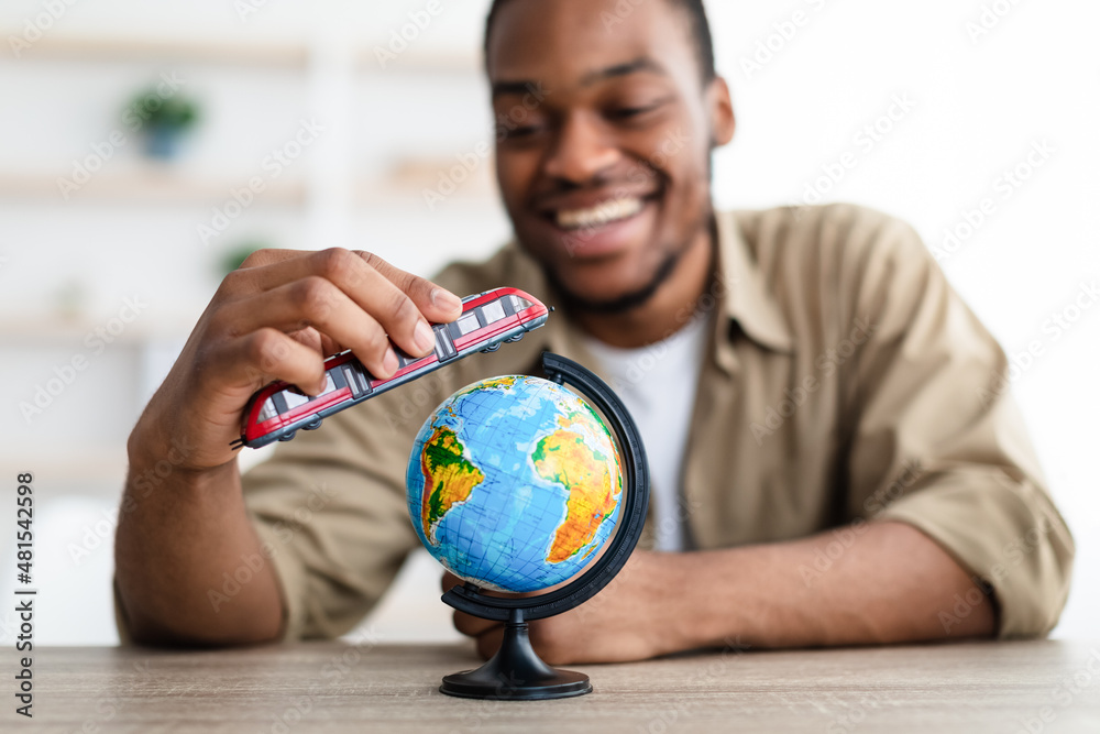 African Guy Playing With Train And Globe Planning Trip Indoors African Guy Playing With Train And Globe Planning Trip Indoors